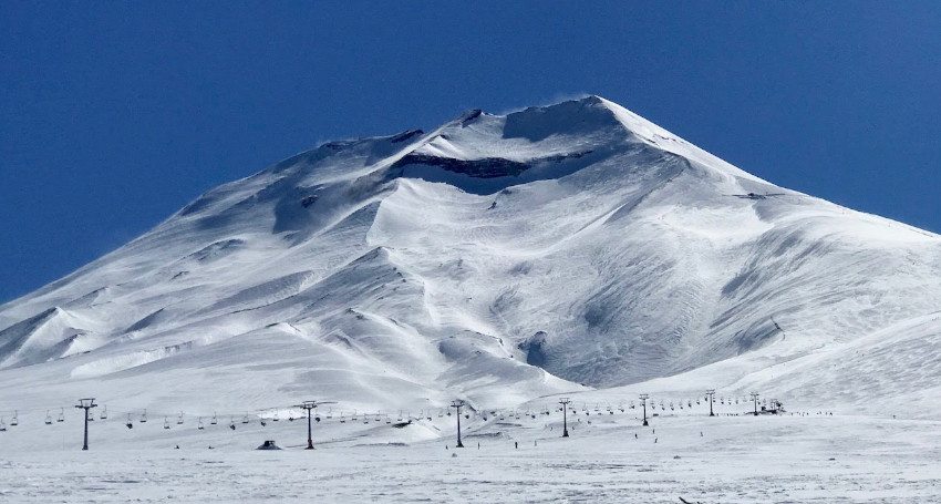 Snow-covered Corralco mountains with ski lifts and a clear blue sky above.