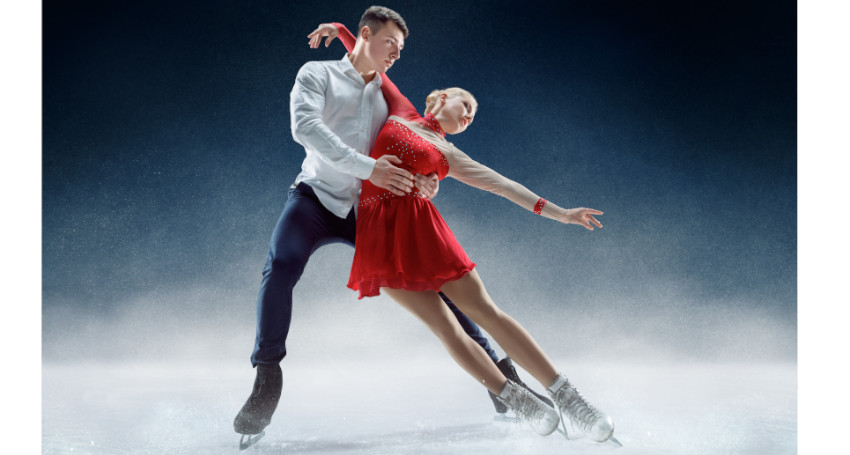 A male and female figure skating duo perform on ice, the man in a white shirt and dark pants, and the woman in a red dress, both in an elegant pose.