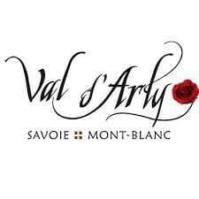 Logo with cursive text "Val d'Arly" featuring a red rose, and smaller text "Savoie Mont-Blanc" below with a small cross symbol between the words "Savoie" and "Mont-Blanc".
