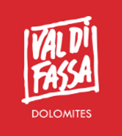 Red graphic with white text reading "Val di Fassa" inside a square, and "Dolomites" below.